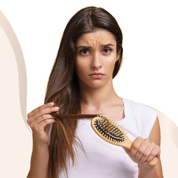 Woman with tangled hair holding a hairbrush, showing hair damage.